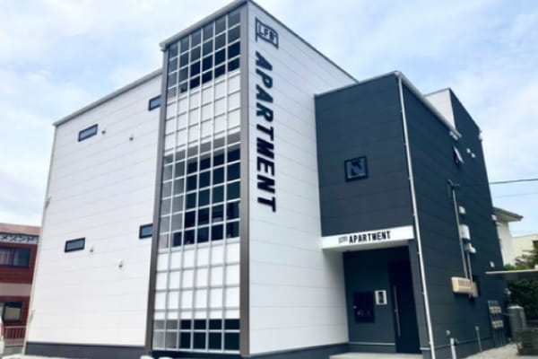 ホワイトとダークグレーの3階建てアパート